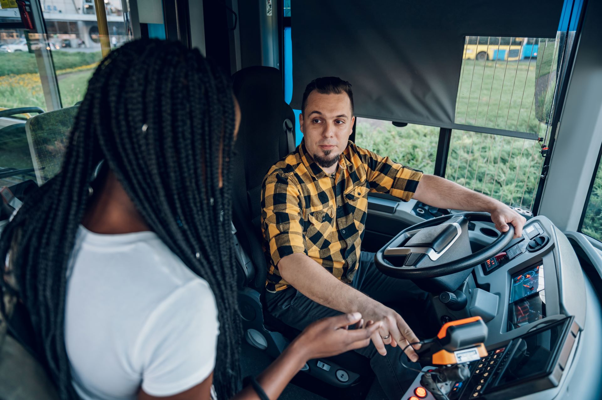 Busfahrer im Fahrerraum im ÖPNV im Gespräch mit Fahrgast