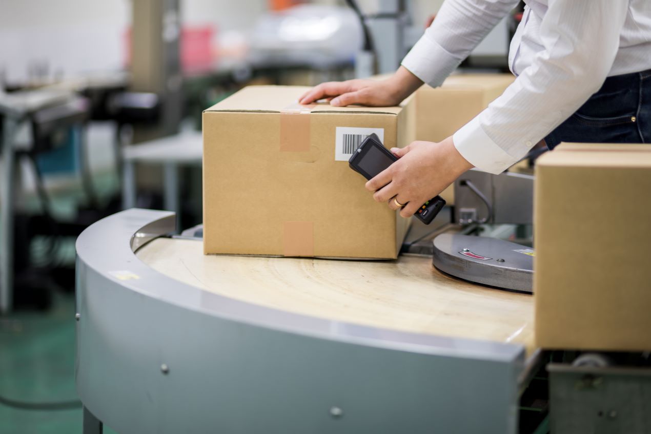 Ein Mitarbeiter scannt ein Paket mit einem mobilen Barcode-Scanner zur schnellen Datenerfassung in der Logistik.