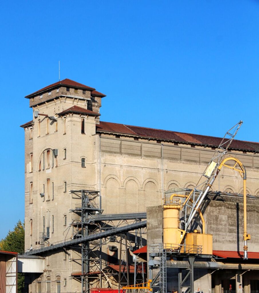 Industrieanlage mit Silo, Fördertechnik und Produktionsgebäude unter blauem Himmel