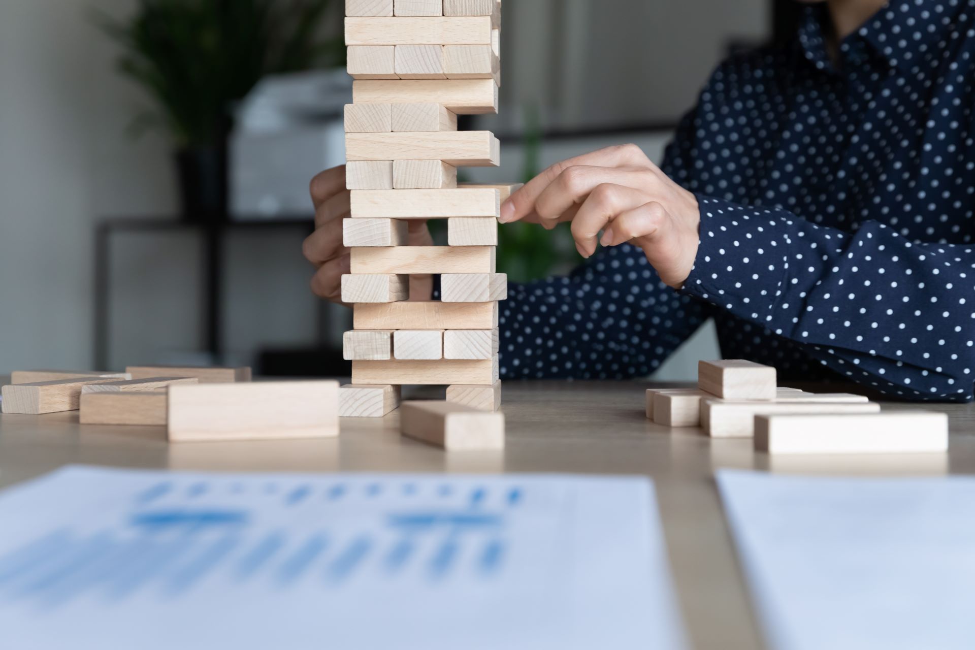 Person stabilisiert Holzturm mit Strategie