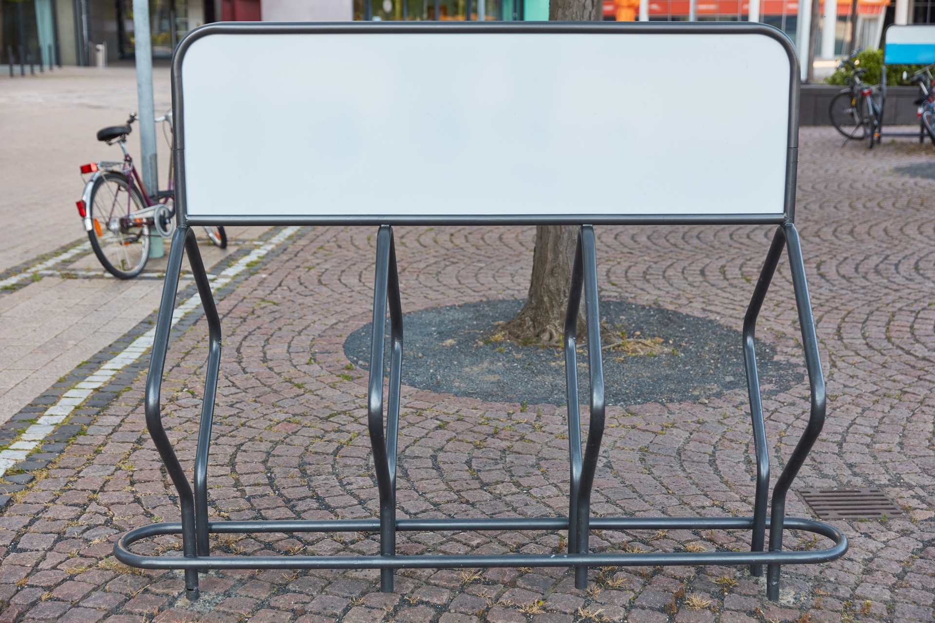 Leeres Metallgestell mit Werbefläche auf gepflastertem Platz | Bauzaunbanner