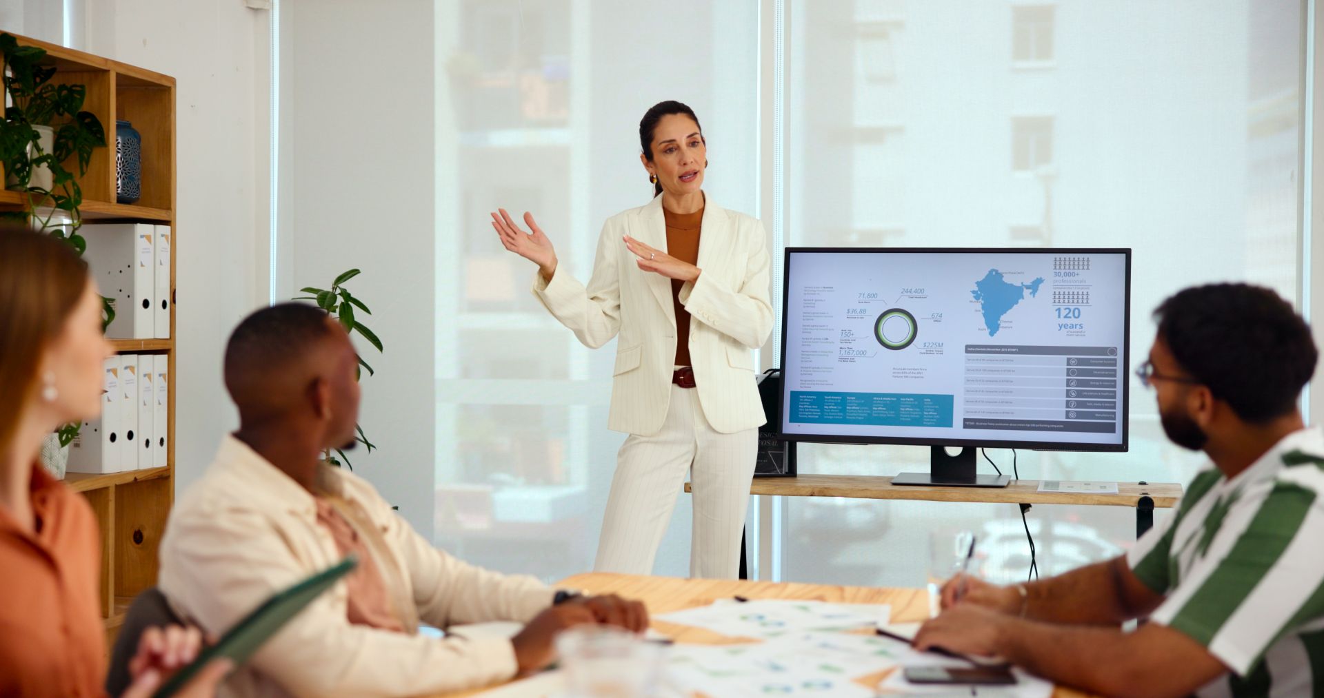 Frau erklärt ein Analyse-Dashboard vor Team in Workshop-Umgebung